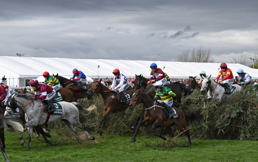 Horses jump a fence in the Grand National 2024 Aintree