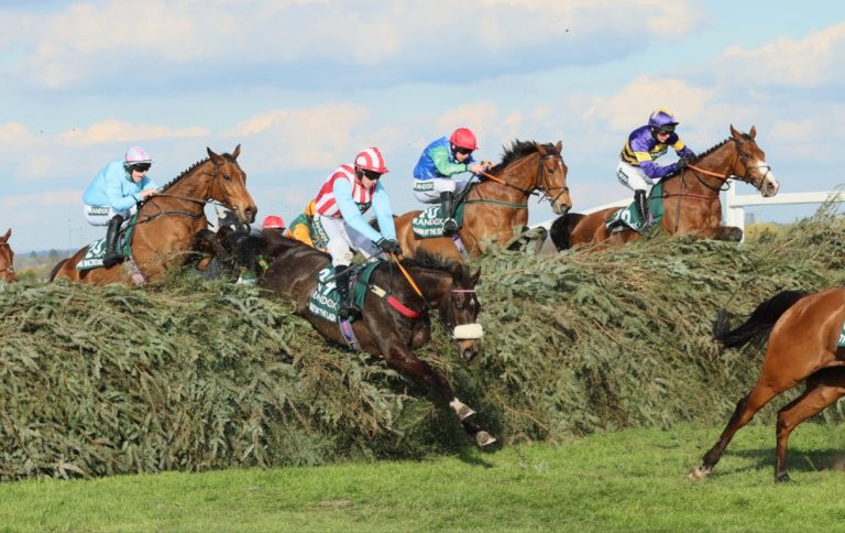 Horses jump a fence in the Aintree Grand National