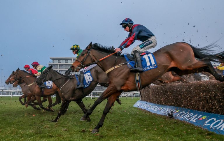 Horses jumping a fence in the Coral Gold Cup at Newbury