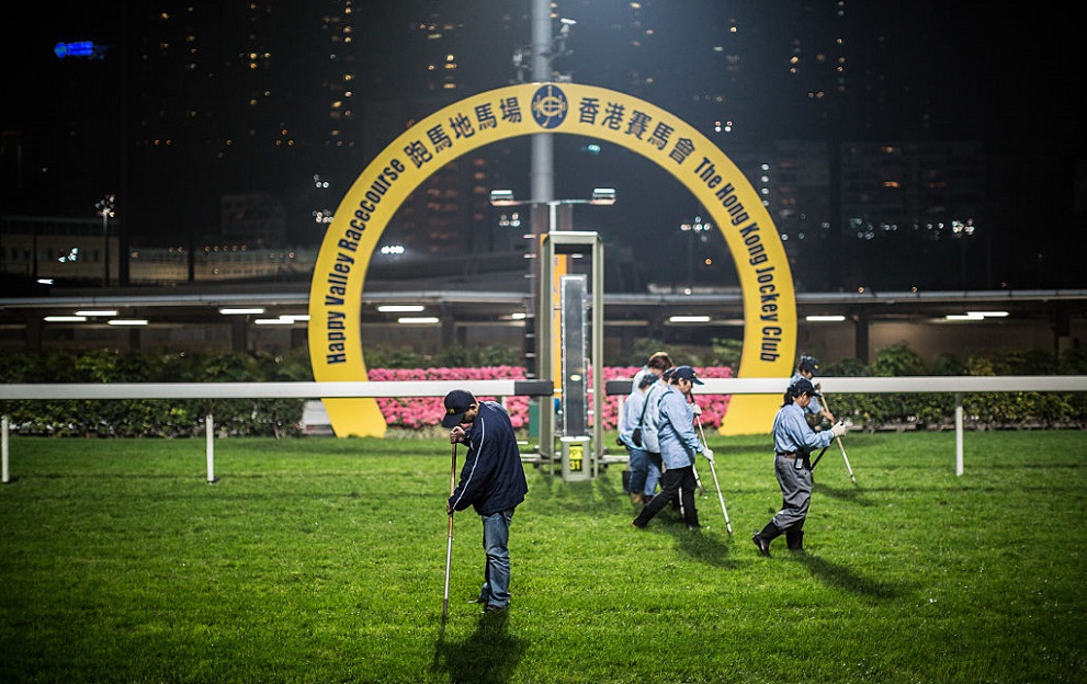 In this picture taken on March 31, 2016, workers repair pieces of upturned turf following a night horse race at the Hong Kong Jockey Club in the Happy Valley district of Hong Kong. Hong Kong has two racecourses, Happy Valley and Sha Tin, with meets on Wednesday and Sundays drawing hardcore enthusiasts glued to form guides, and casual visitors more interested in a cold beer than the horses. / AFP / Anthony WALLACE / To go with AFP story "HongKong-racing-economy, FEATURE" by Dennis Chong (Photo credit should read ANTHONY WALLACE/AFP via Getty Images)