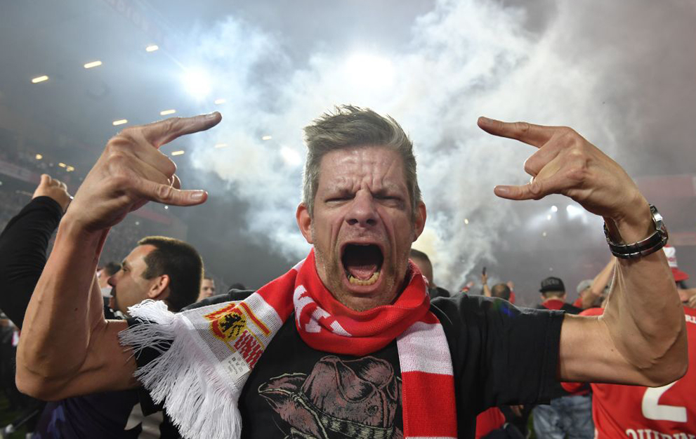An Union Berlin's fan celebrates on the pitch after Union won in the German Bundesliga Relegation second-leg football match FC Union Berlin v VfB Stuttgart in Berlin, on May 27, 2019. (Photo by John MACDOUGALL / AFP) / DFL REGULATIONS PROHIBIT ANY USE OF PHOTOGRAPHS AS IMAGE SEQUENCES AND/OR QUASI-VIDEO (Photo credit should read JOHN MACDOUGALL/AFP via Getty Images)
