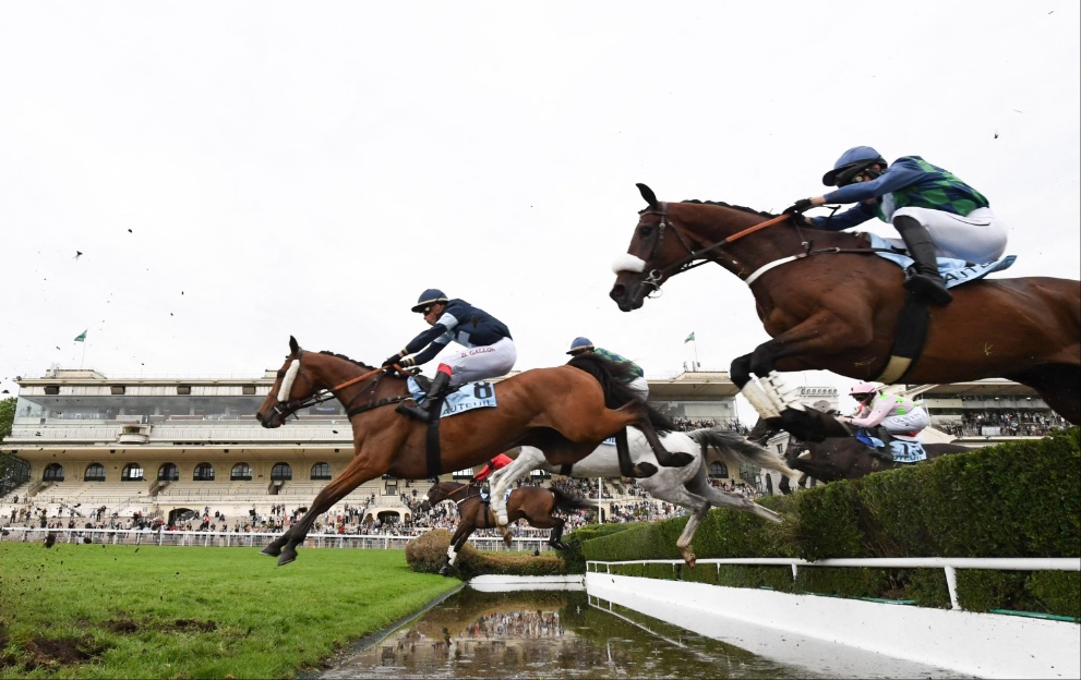 Horses jump a fence in the Grand Steeple-Chase de Paris